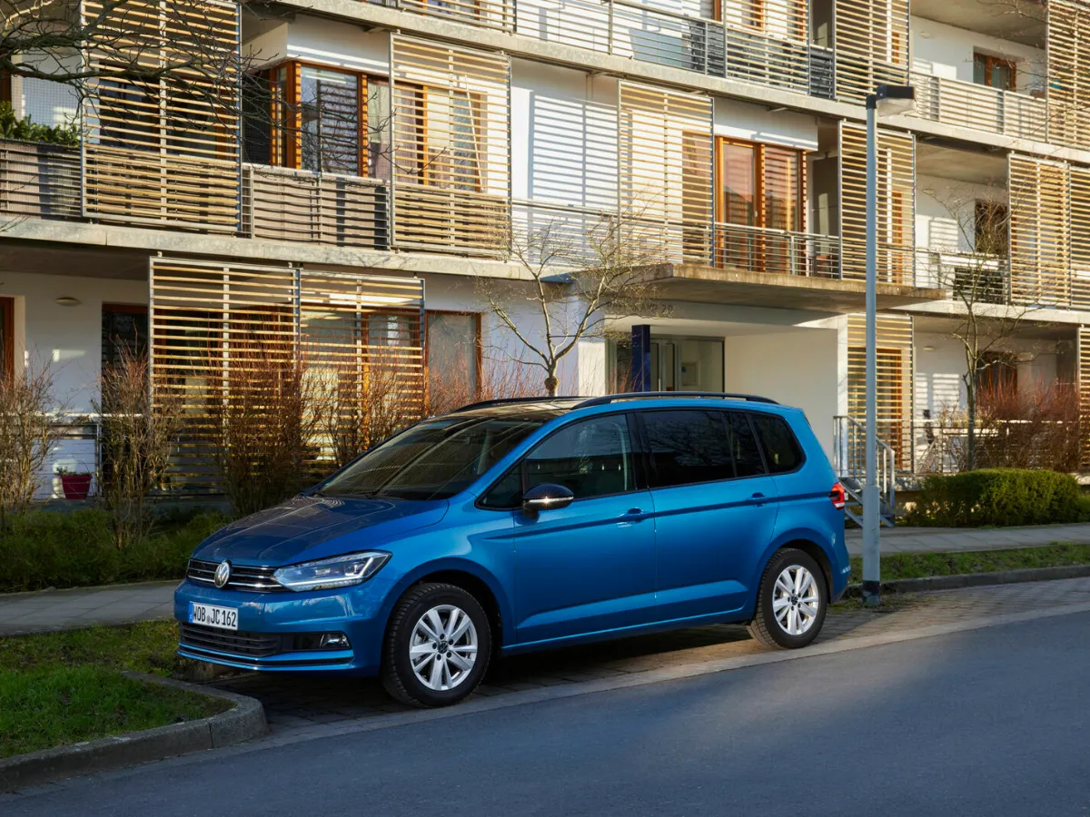 Volkswagen Touran in blue, in front of a house