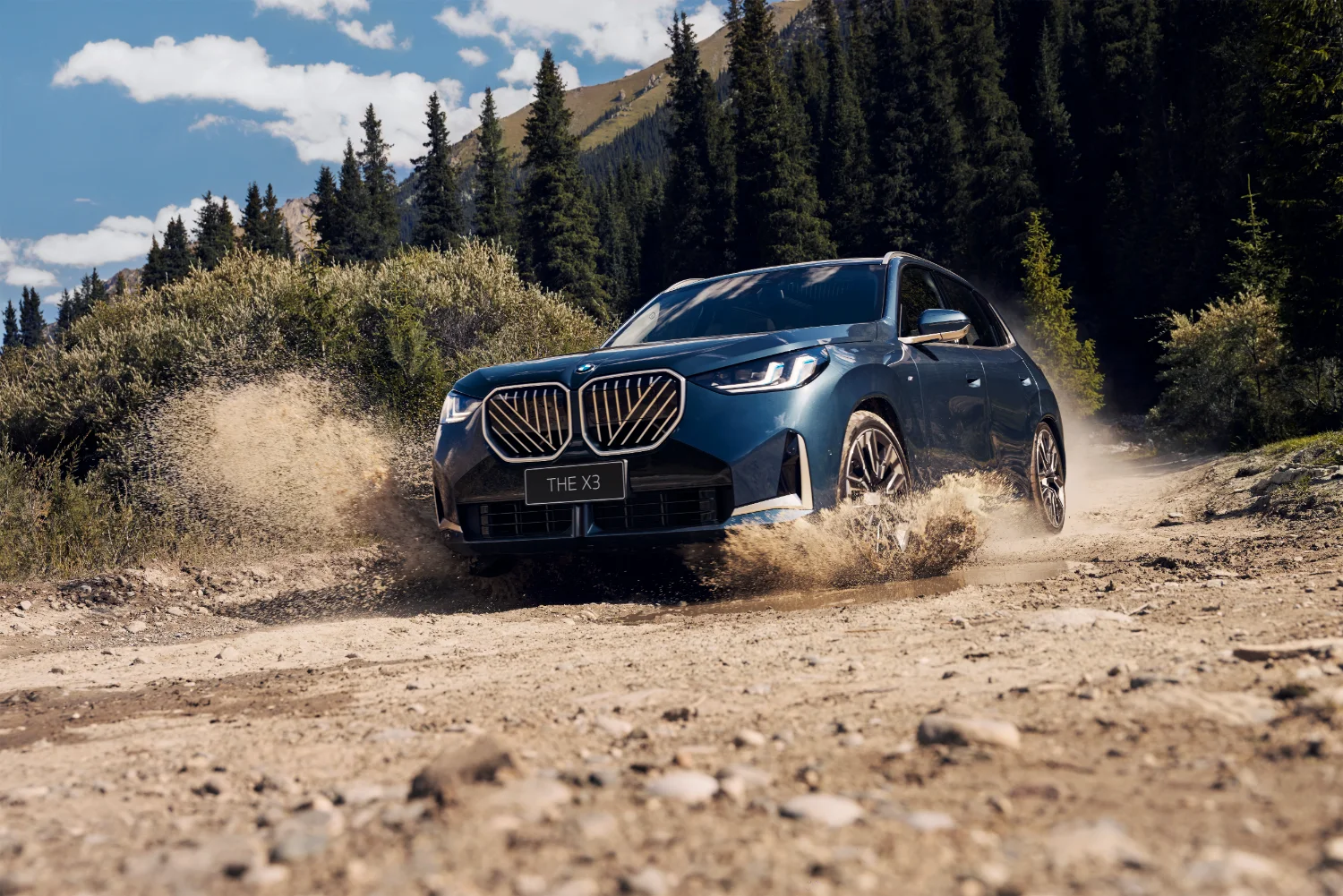 BMW X3 in Blau, im Gelände in Fahrt